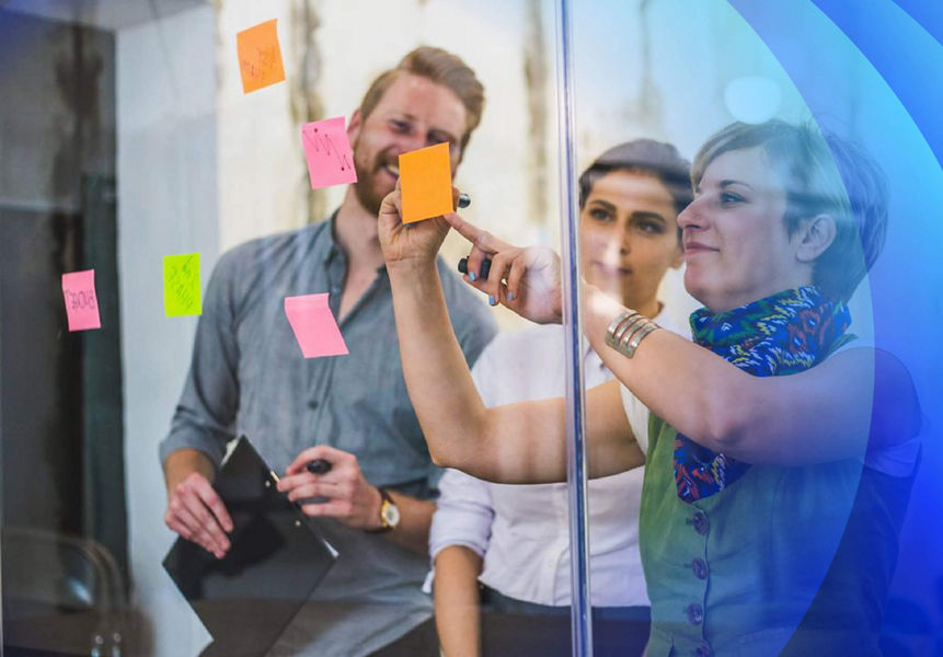 A women writing on a post-it note in a strategy workshop with her team