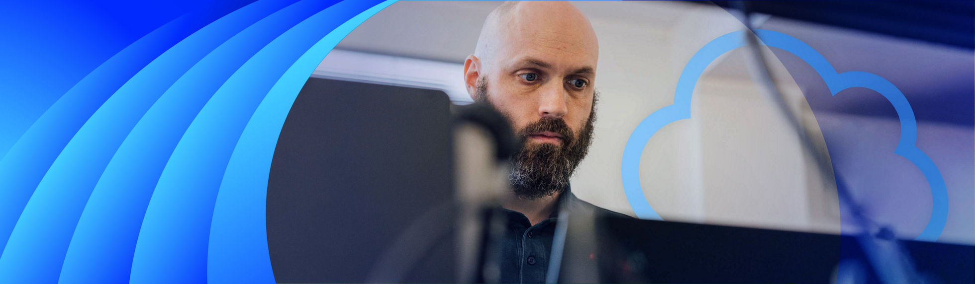 A Datacom technician with a beard working on a laptop with a floating cloud