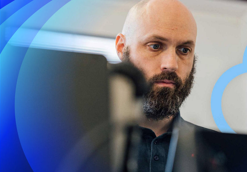A Datacom technician with a beard working on a laptop with a floating cloud