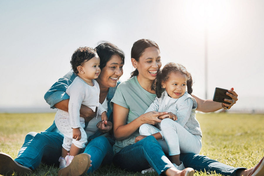 Family sitting on a grassy hill taking a selfie