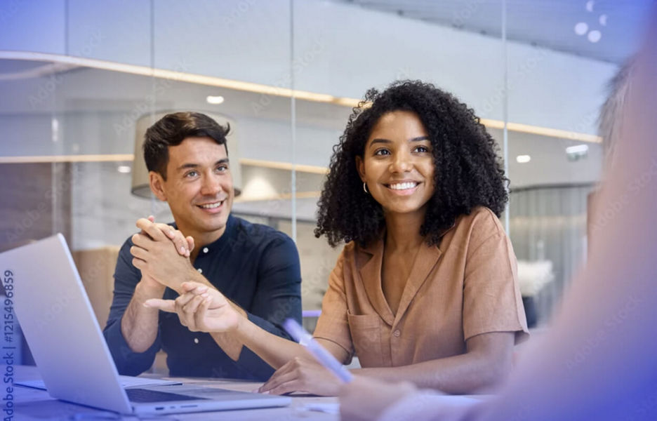 Two professionals are sitting at a desk with a laptop in front of them, discussing business management solution with a consultant. 