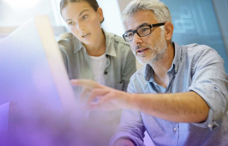 Man and women in an office looking at monitor