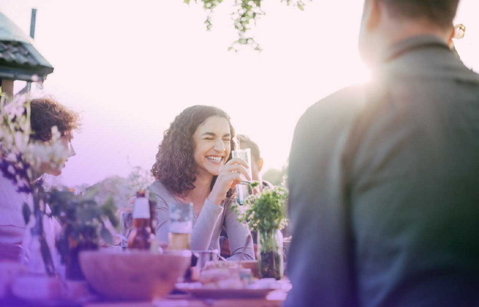 Women in a dinner table holding a drink and laughing