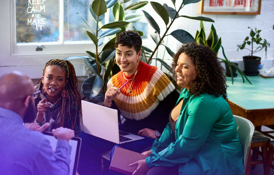 Group of people sitting and talking together with laptops on their laps