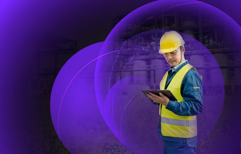 A man holding an iPad while wearing protective gear at a construction site