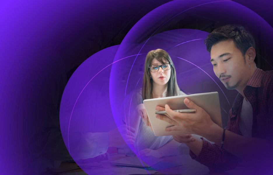 Two colleagues sitting at a table in an office while looking at an iPad