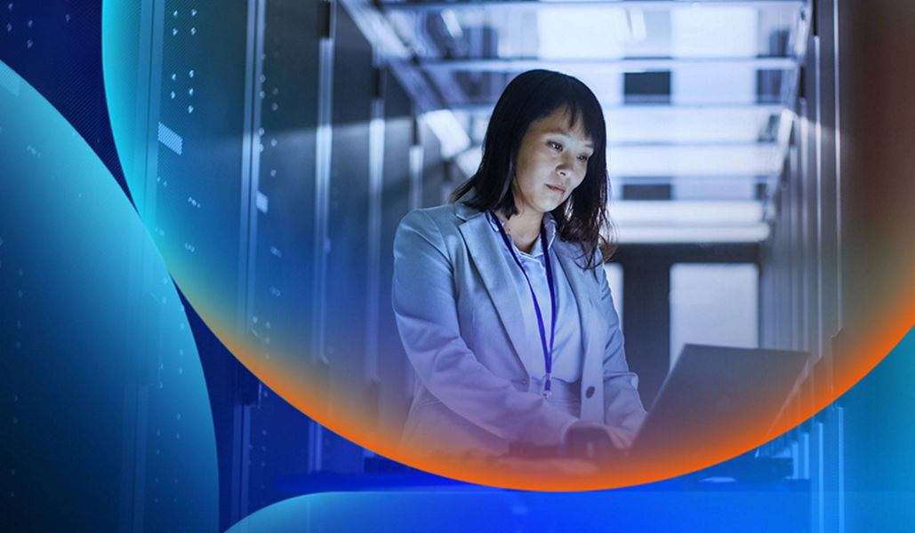 A woman working on a laptop in a dark room with servers with an orange and blue lens overlay