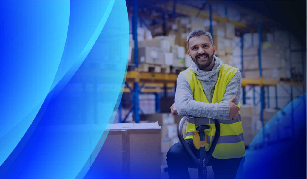 A smiling man leaning on a palette trolley in a warehouse