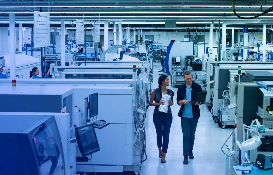 Man and women in a office lab walking while looking at laptop screen