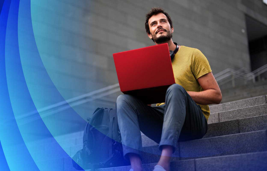 Man with laptop sitting on stairs looking out to the distance