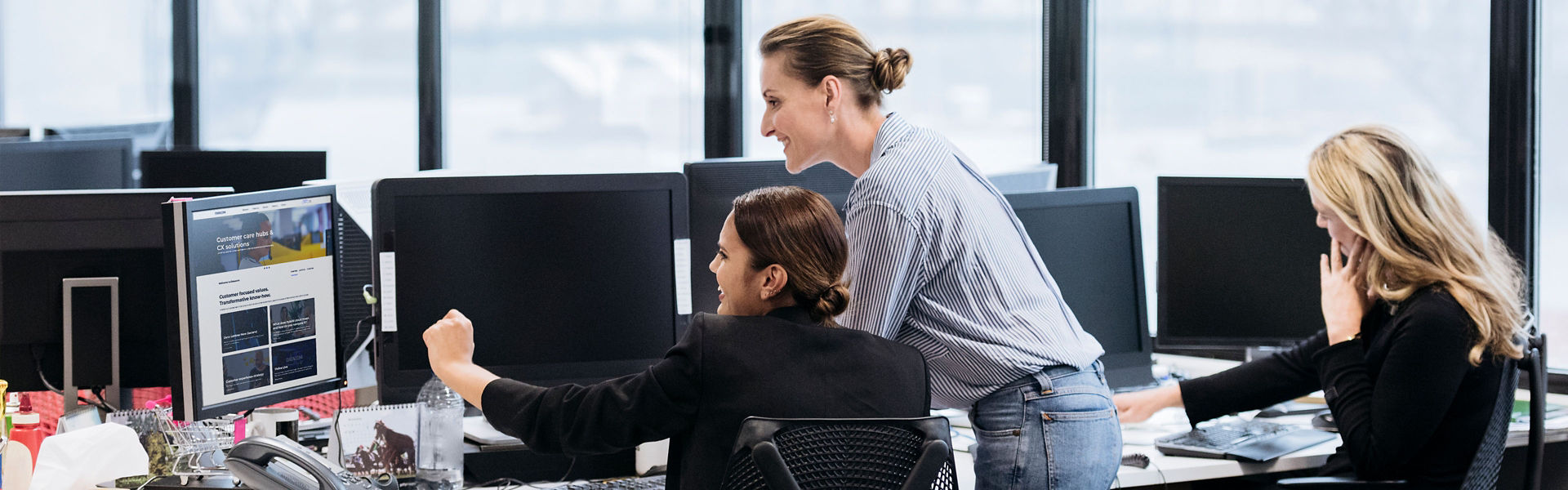 Women in an office smiling and looking at a computer