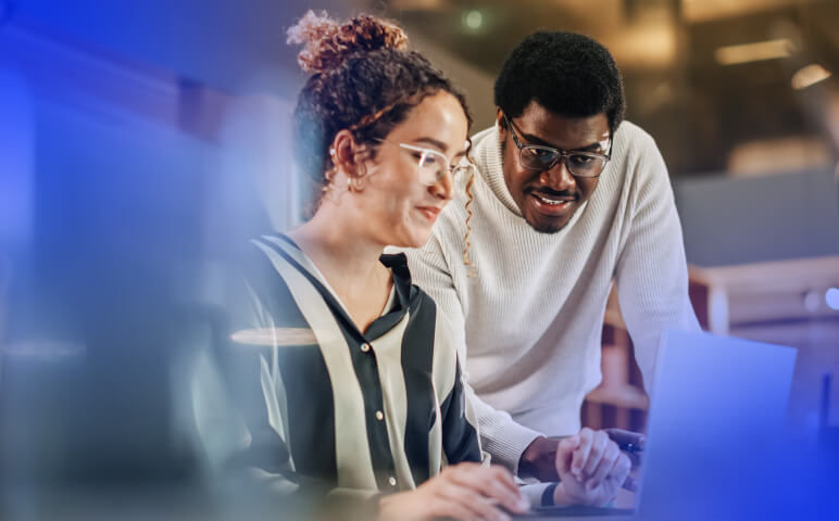 Man and woman at desk looking at laptop