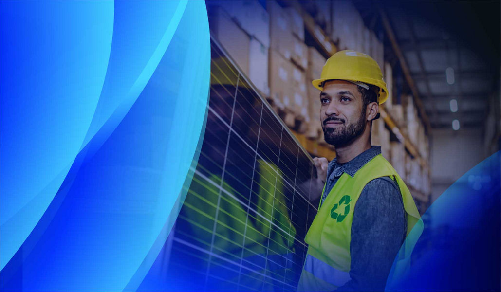 A man wearing a sustainability vest carrying a solar panel in a warehouse