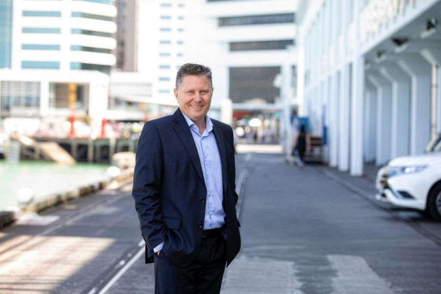 Mark Hardie, Director of Product Solutions Group and Strategic Partnerships at Datacom, mid body shot standing in the street with office buildings blurred in the background, wearing a navy blue suit and light blue shirt