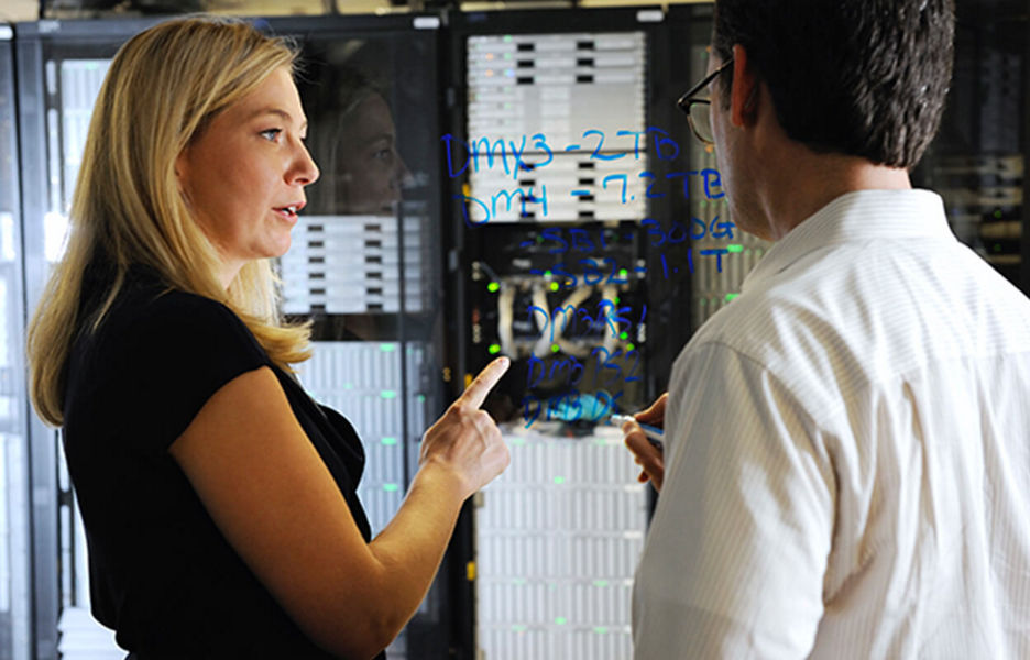 IT professional explaining work to another person in front of a server room