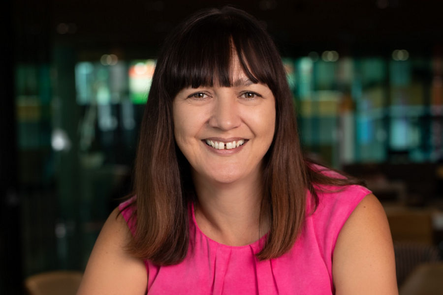 Portrait of Suz Miller smiling, wearing pink shirt