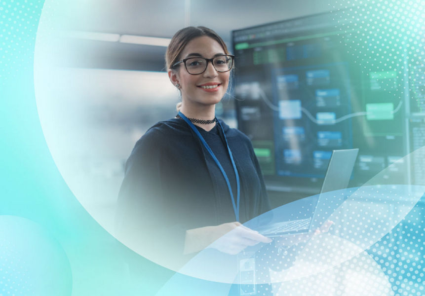 A smiling AI expert holds a laptop in a room with a large screen displaying system architecture.