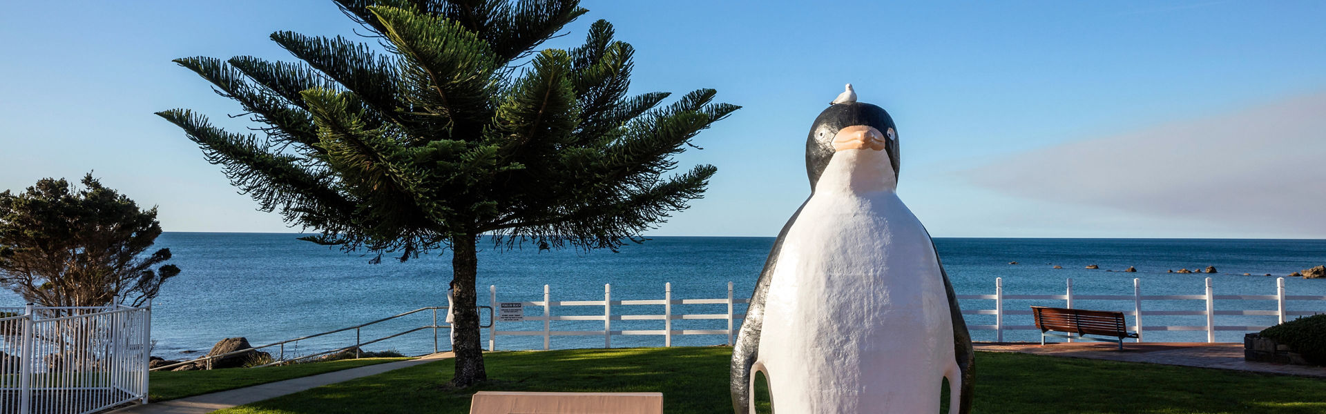 Photograph of a coastal scene in Tasmania with penguin statue and tree