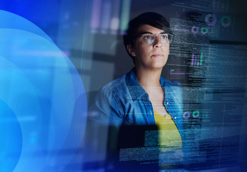 A Technical Lead working in front of a computer screen displaying various data visualisations and code. 