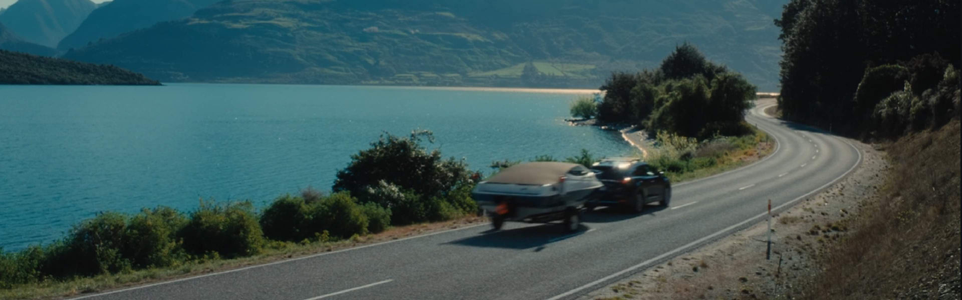 Car with boat attached driving a scenic route 