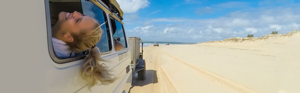 girl laughing holding her head out of a vehicle travelling on the dunes