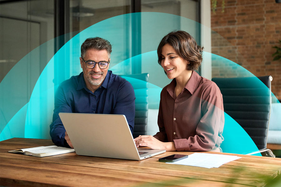 Two payroll people sitting at a desk with a laptop