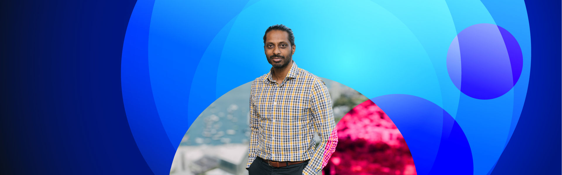 Image of Vickesh Kambaran standing in front of a background of circles in various shades of blue 
