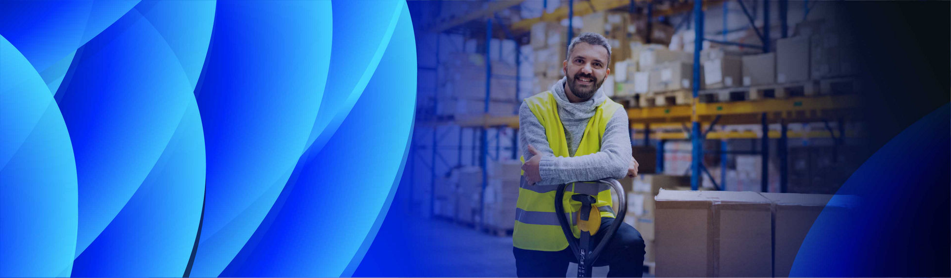 A smiling man leaning on a palette trolley in a warehouse