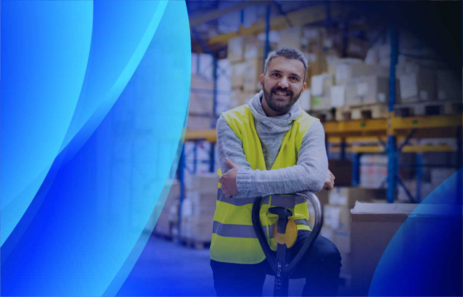 A smiling man leaning on a palette trolley in a warehouse