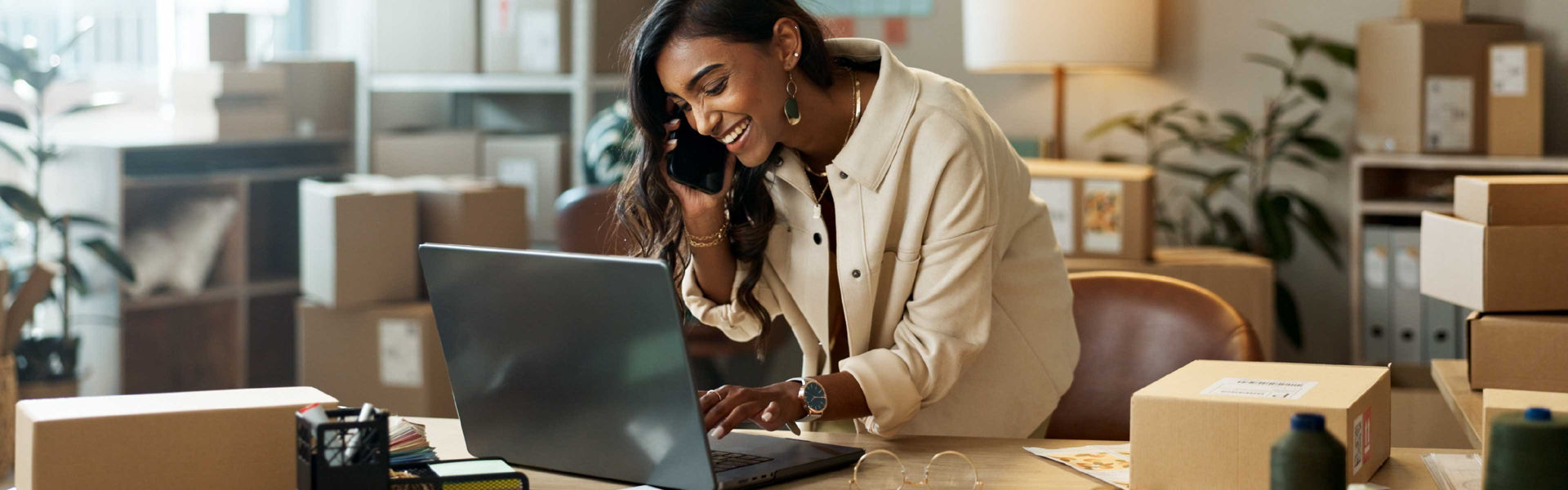 Happy women with a laptop while on a phonecall, in a small business office