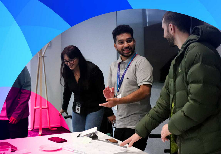 A group of graduates standing at a desk in a workshop
