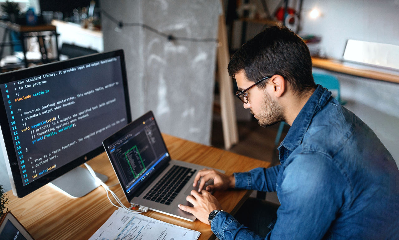Man reading code on computer screens