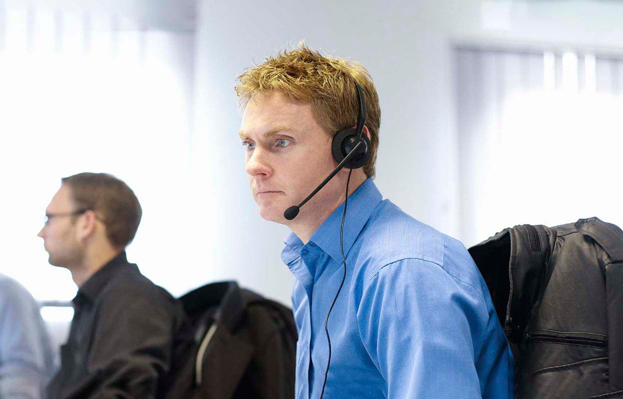 An IT expert with a headset using a computer in an office