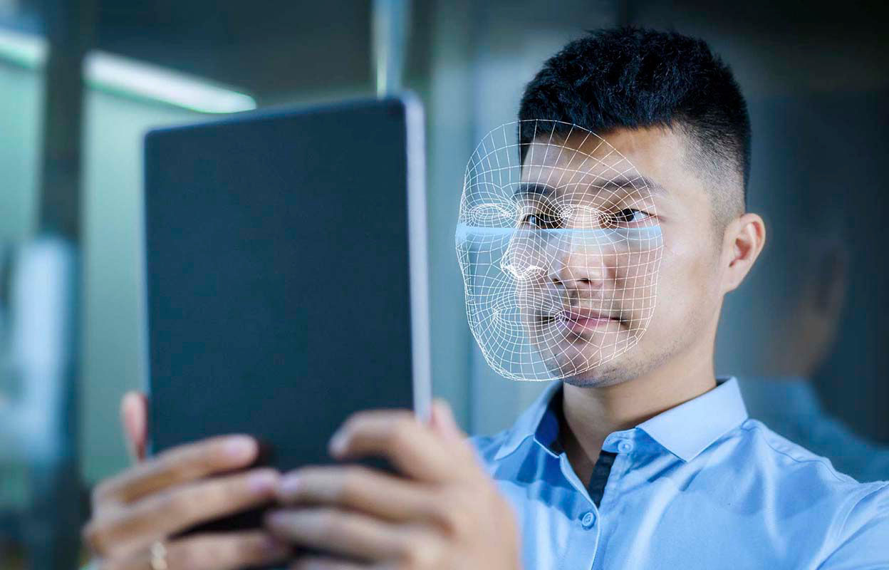 A man holding a tablet up in front of his face