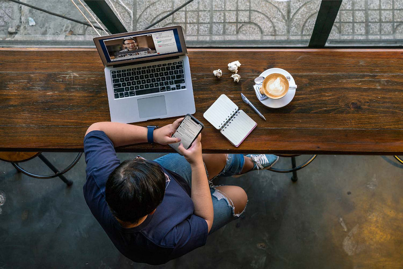 Man at a cafe working on several devices