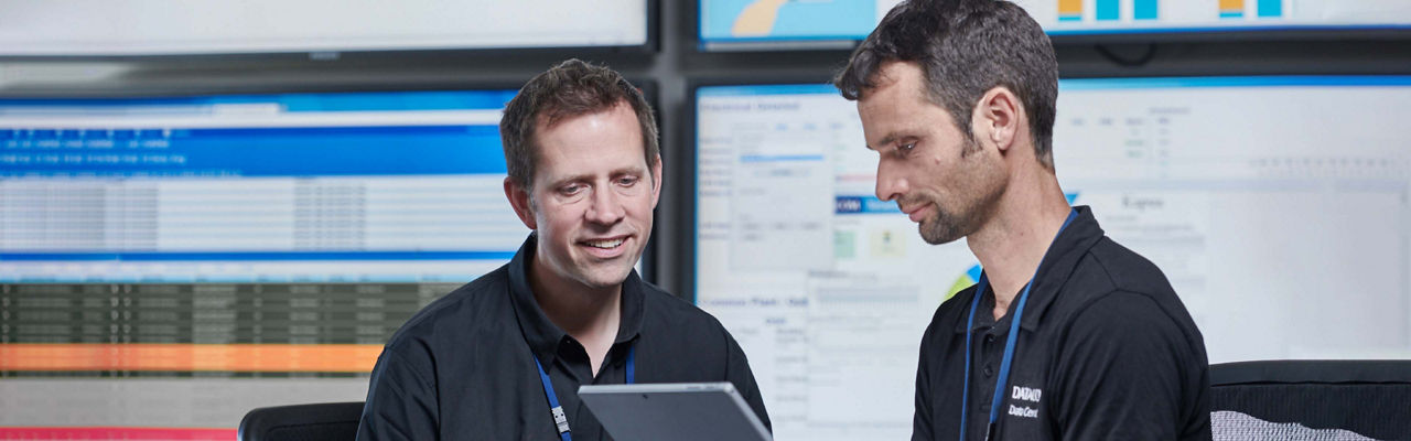 Two men with large screens behind them