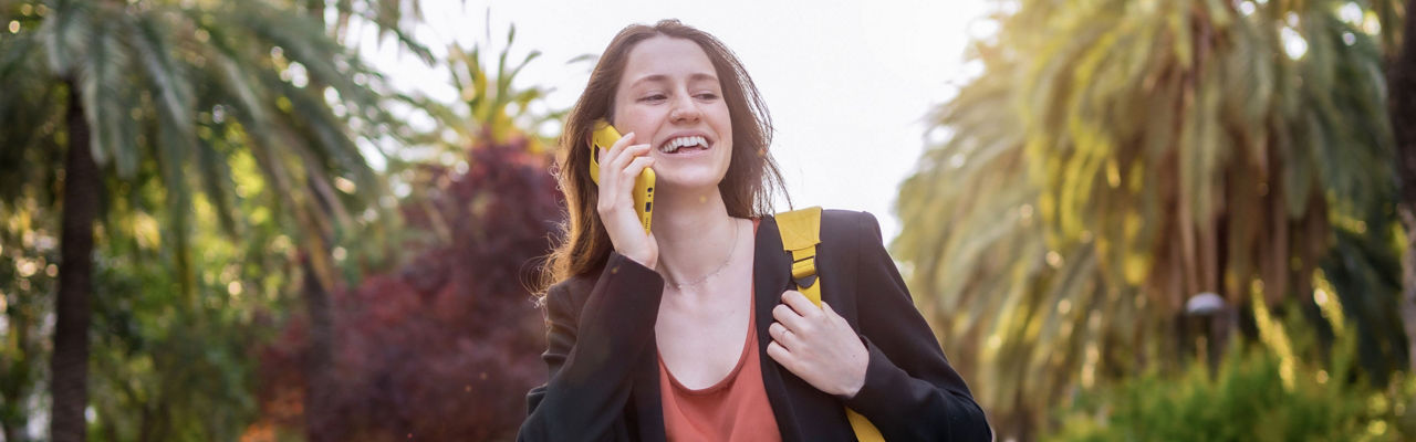 happy girl talking on her phone carrying a backpack
