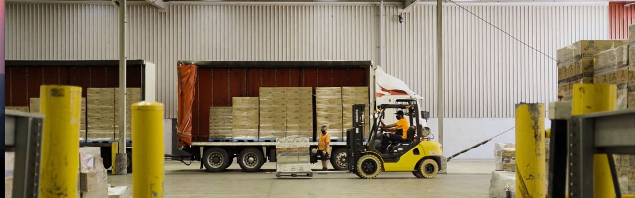 A truck inside a warehouse with pallets being unloaded