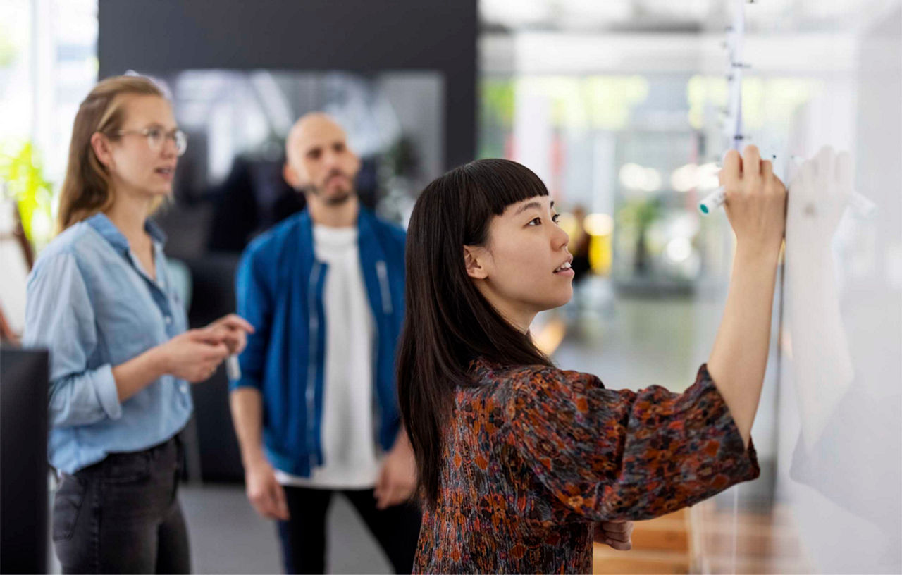 A group of people running a workshop with a woman writing on a whiteboard