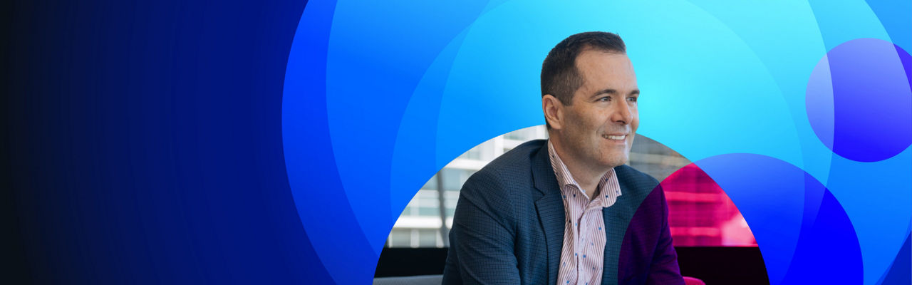 Photo of Darren Keall on a dark blue background with light blue circles.