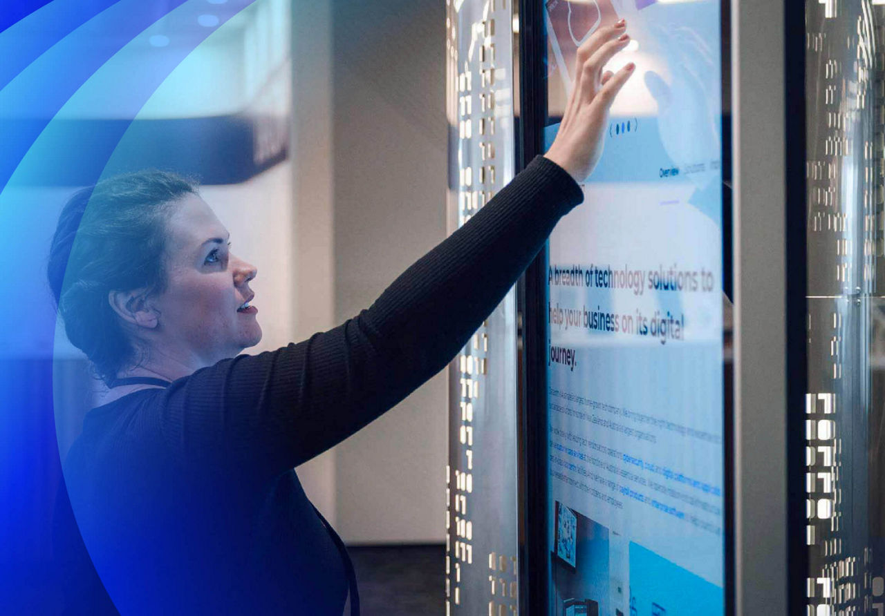 A person reaching out to touch a large display screen