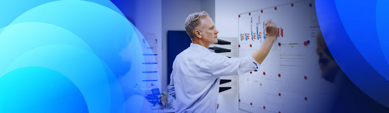 A man writing on a whiteboard in a team meeting