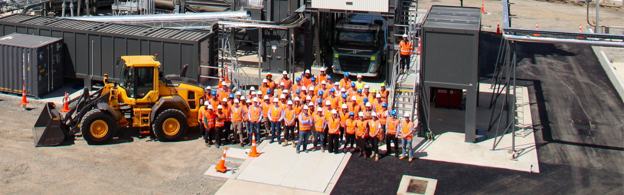 Team of tradespeople wearing high visibility orange safety gear standing as a group