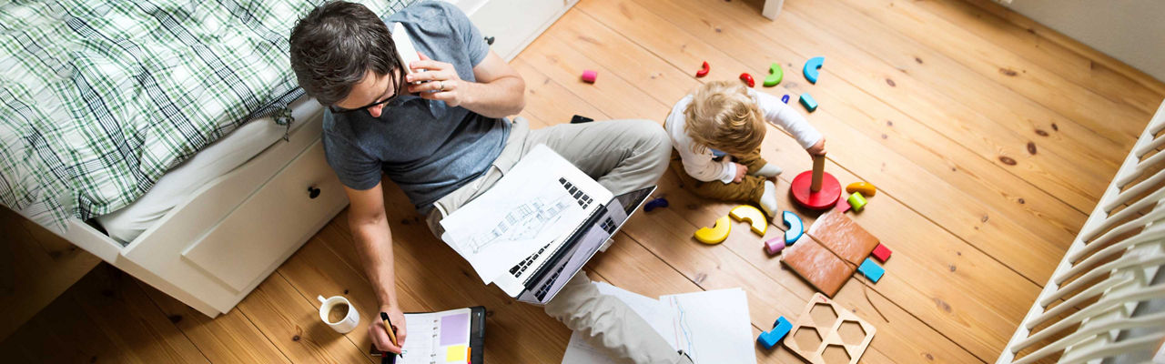 A parent works at home while a child plays