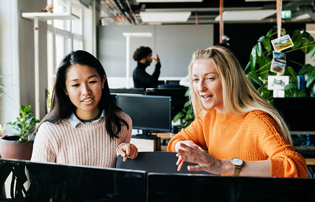 two women discussing next to laptop