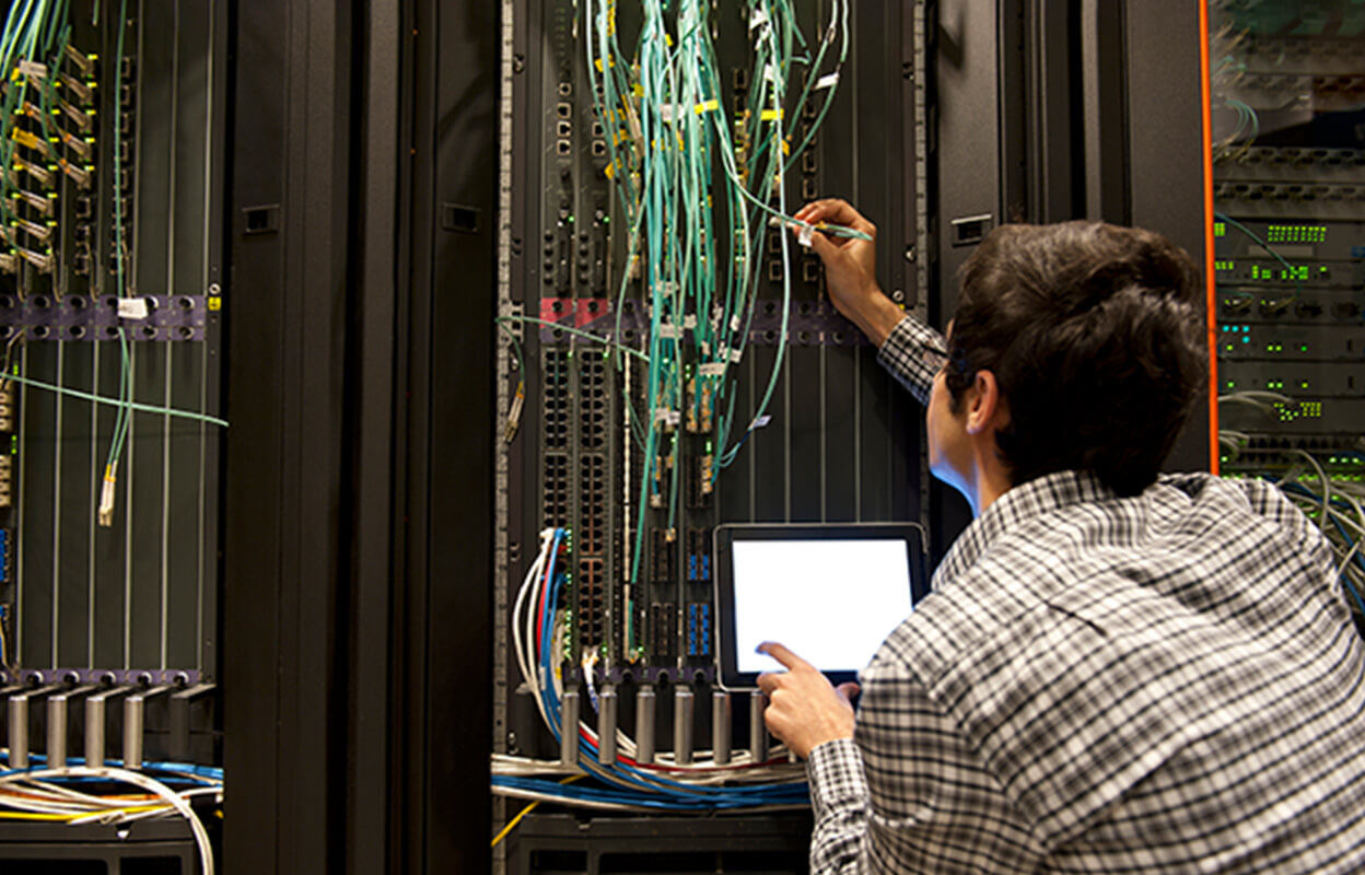 A man holding a device inside a server room