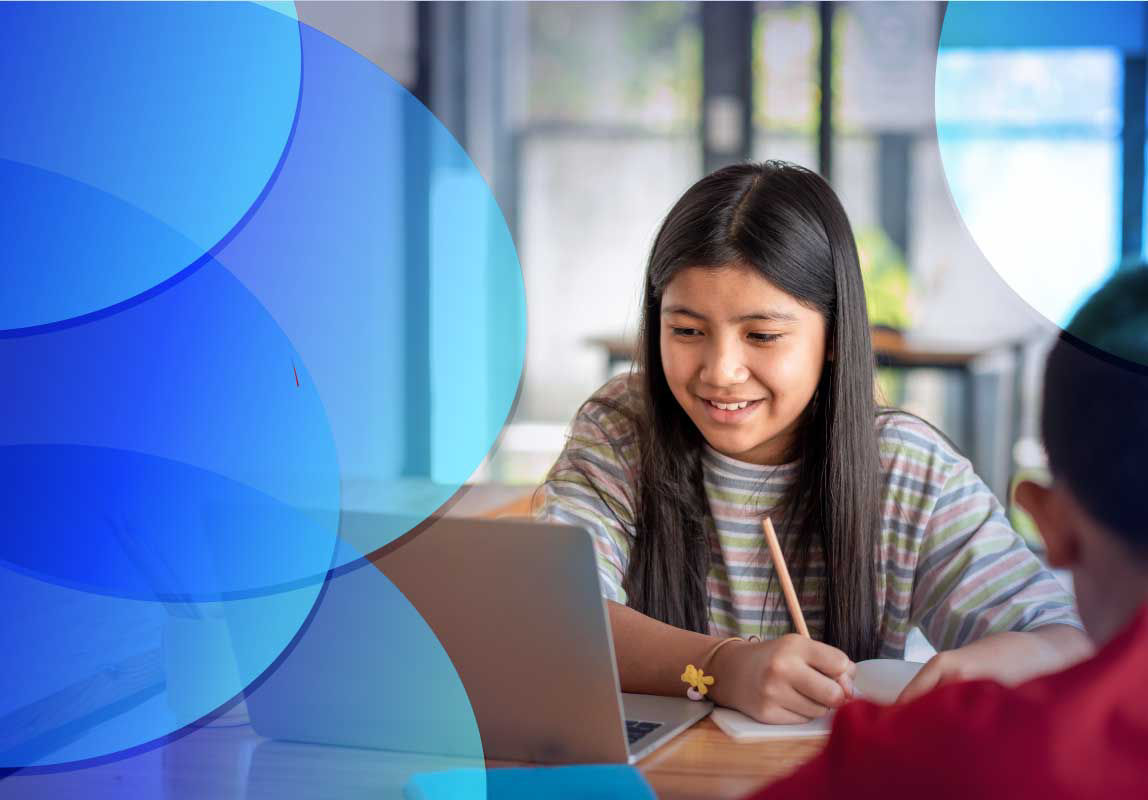 Smiling young girl learning online using laptop