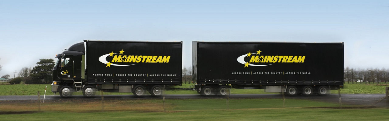 Mainstream black truck with yellow and white logo driving on country road