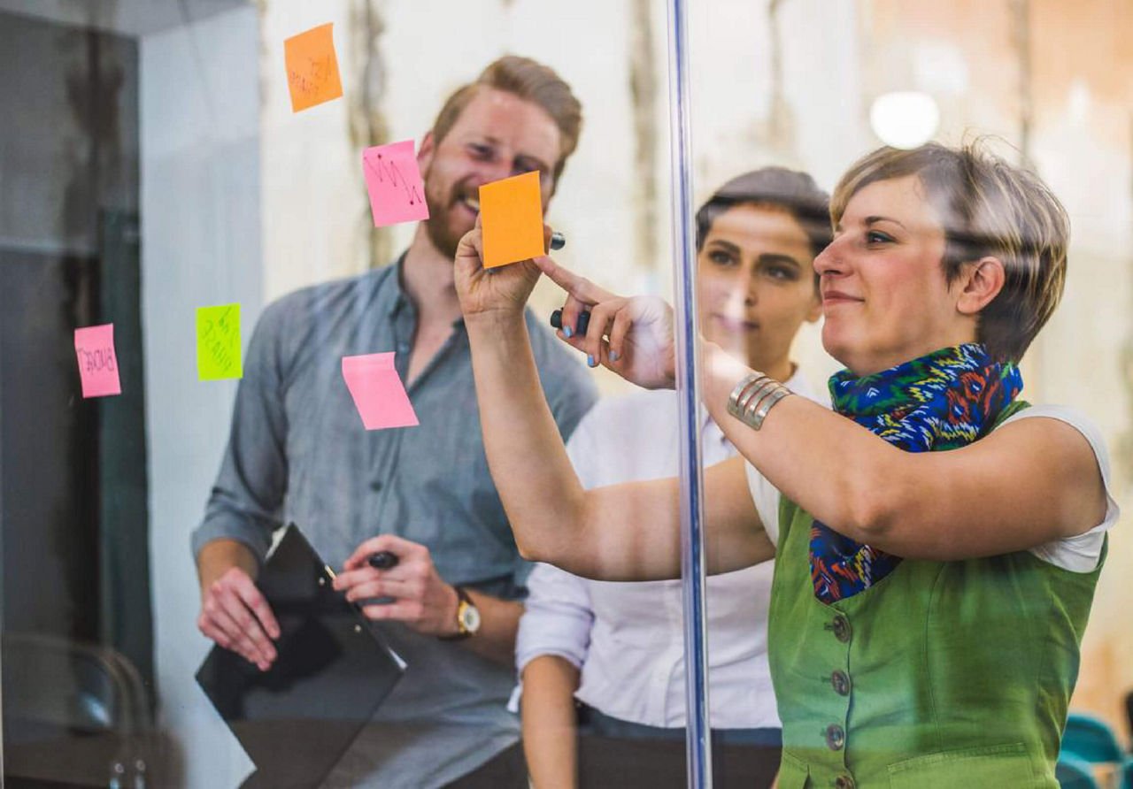 Three colleagues using sticky notes on a whiteboard