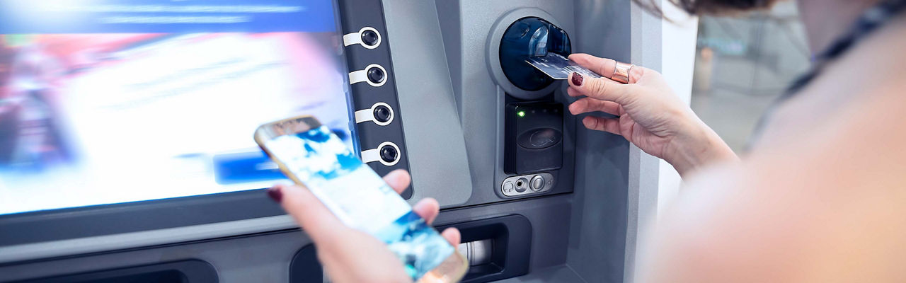 Woman using her phone at an ATM